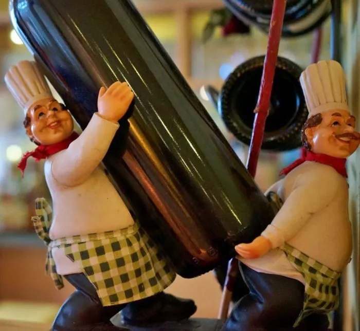 Zwei Koch-Figuren tragen eine Weinflasche – Dekoration im Lokal